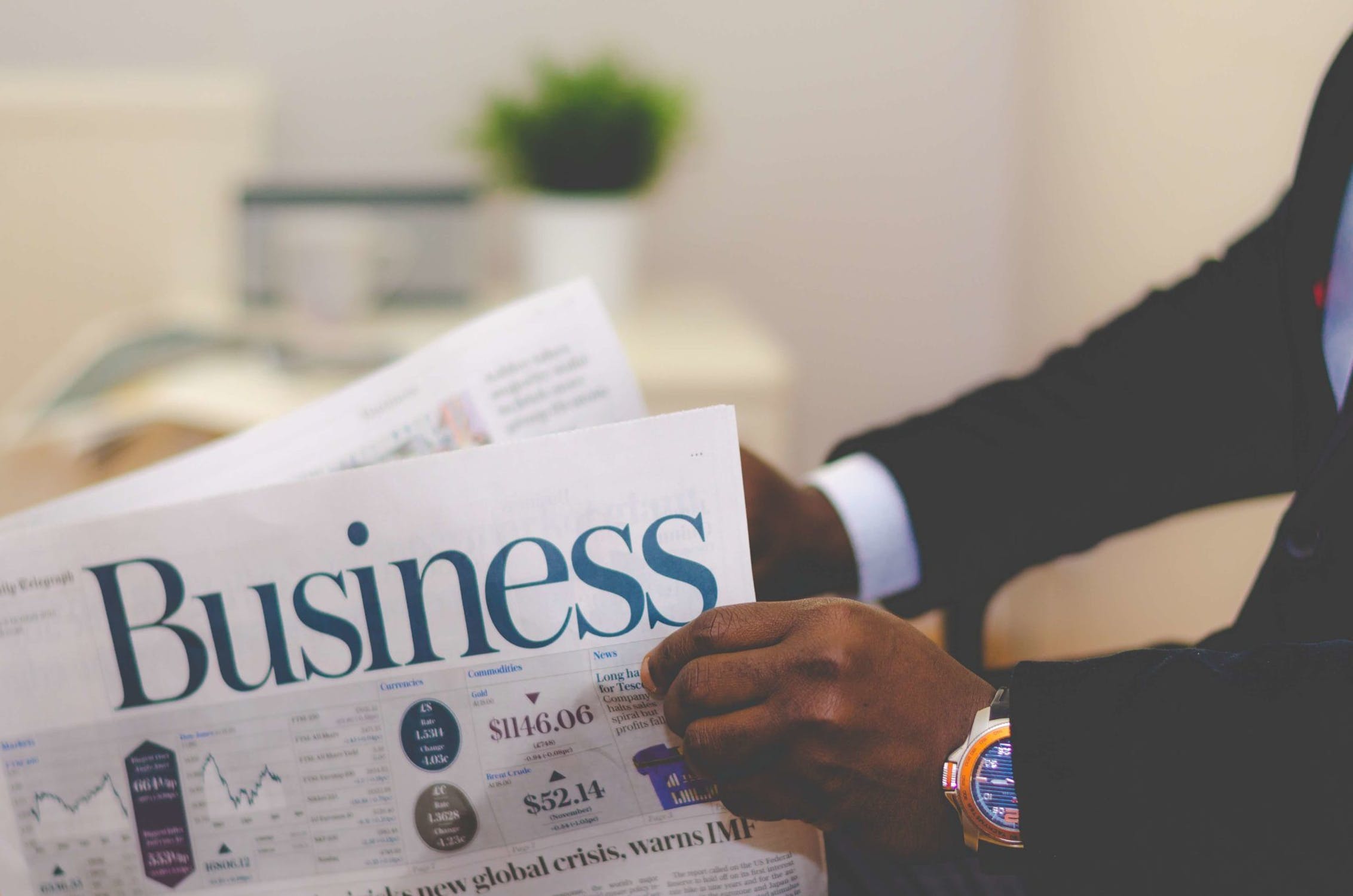 Hands of a man in a suit with the business section of a newspaper.