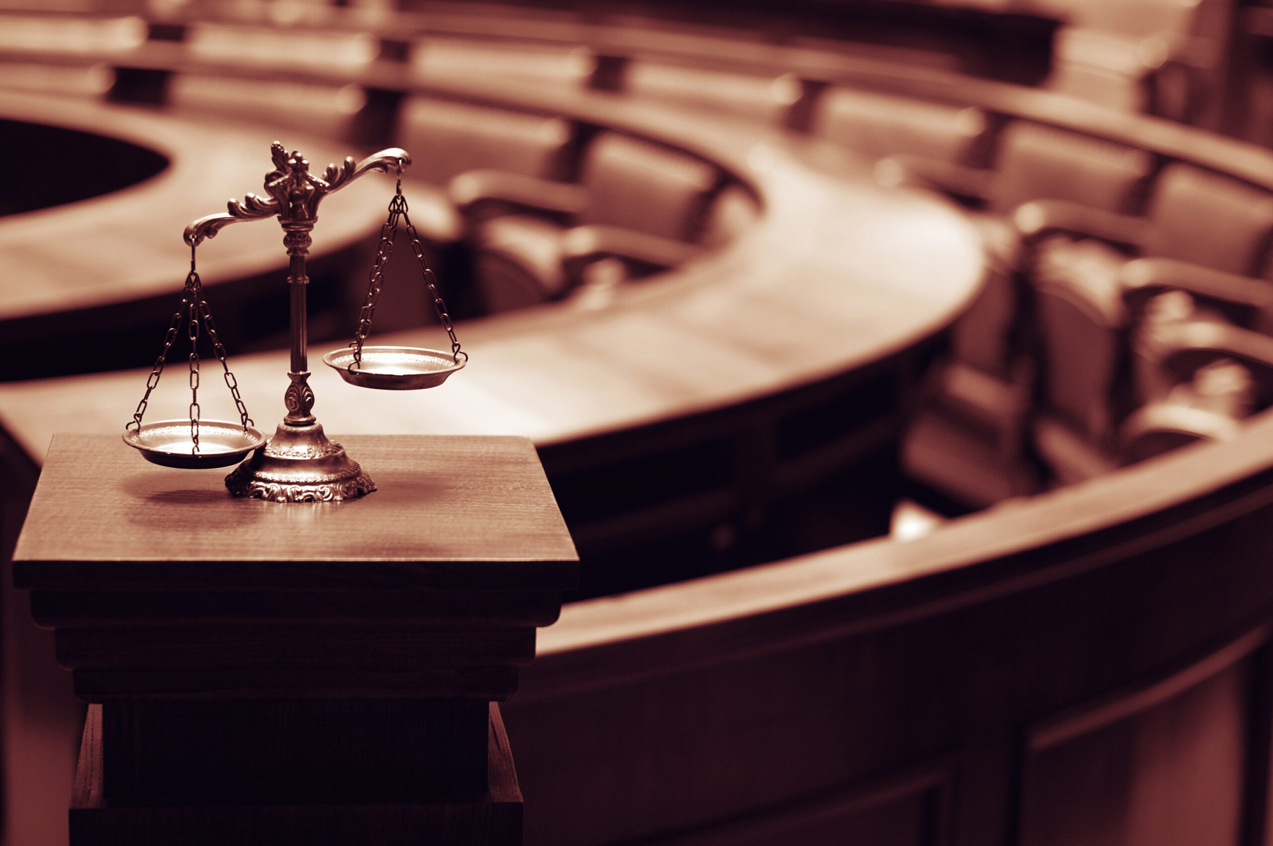 Scales of justice on a pedestal in an empty courtroom